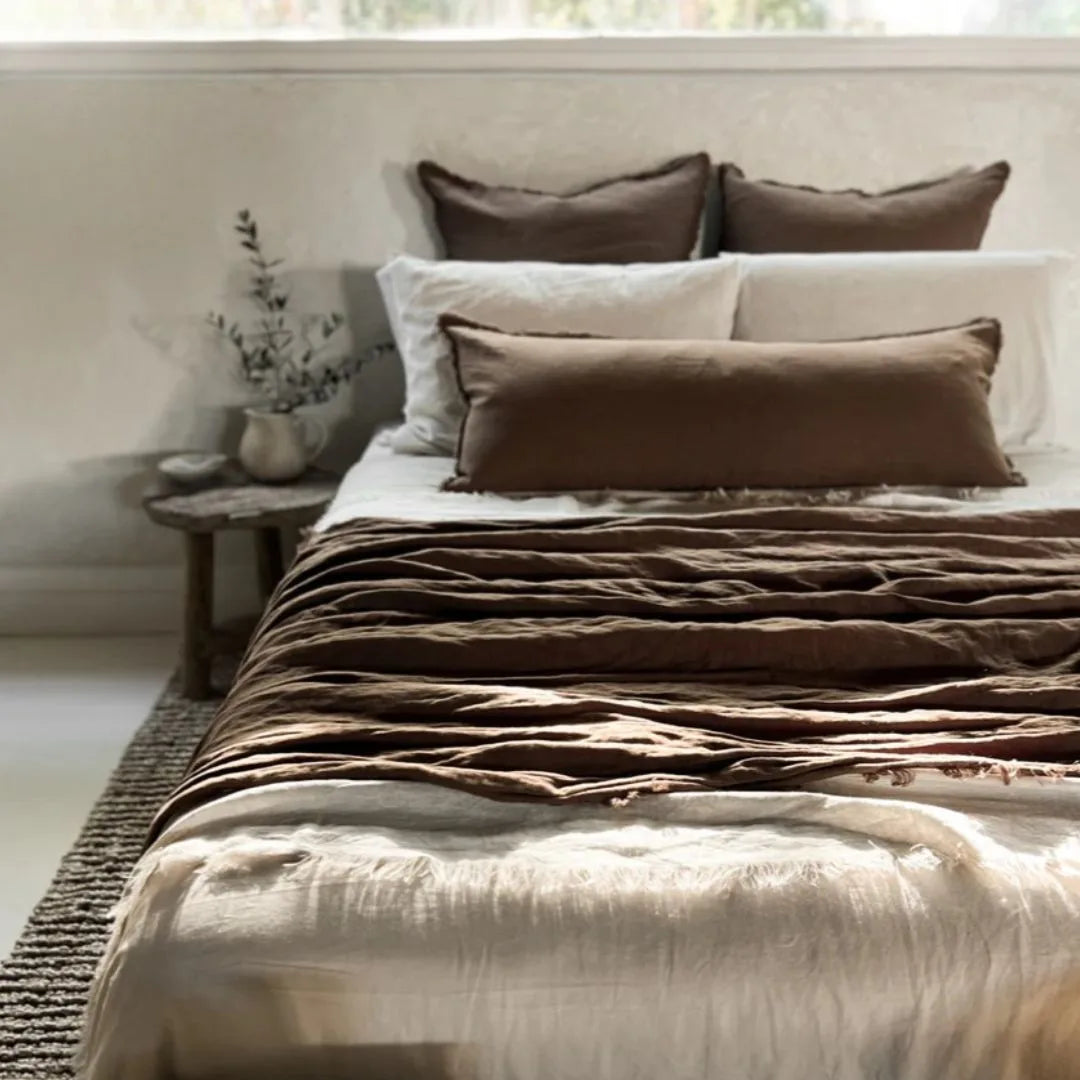 Bed with brown and beige bedding in a softly lit room.