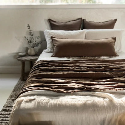Bed with brown and beige bedding in a softly lit room.