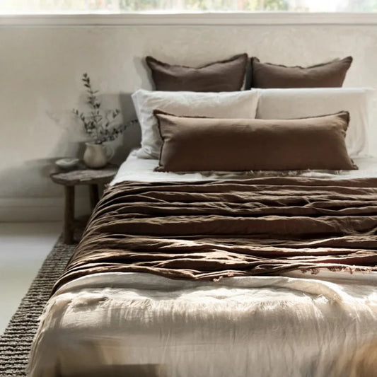 Bed with brown and beige bedding in a softly lit room.
