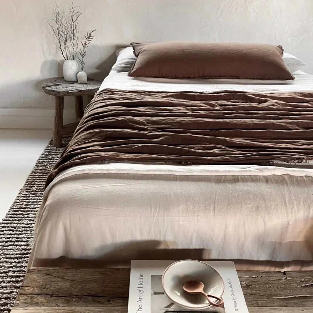 Bed with brown bedding and a wooden side table in a bedroom setting