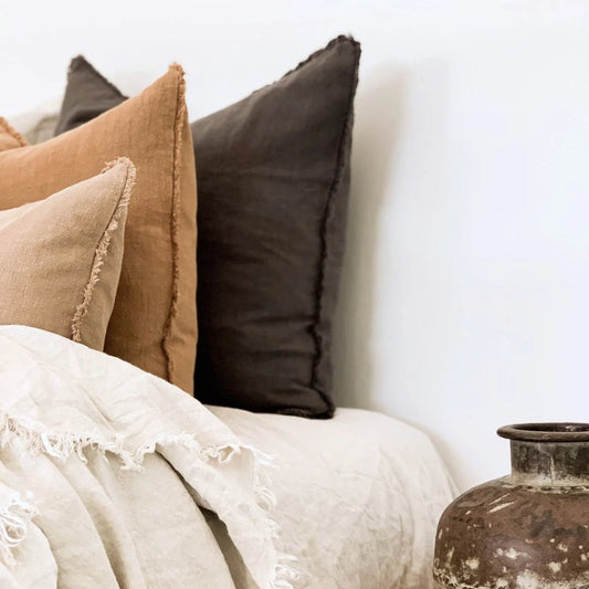Decorative pillows and a vase on a white surface with a blurred background