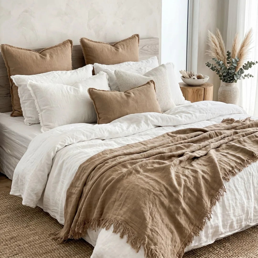 Neatly made bed with white and brown bedding in a bedroom setting.