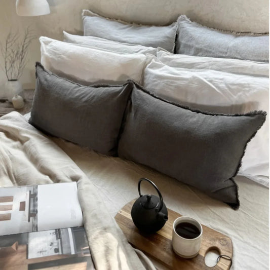 Cozy bedroom scene with pillows, a teapot, and coffee on a tray.
