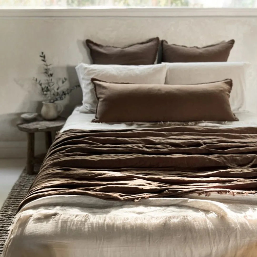 Bed with brown and beige bedding in a bedroom setting
