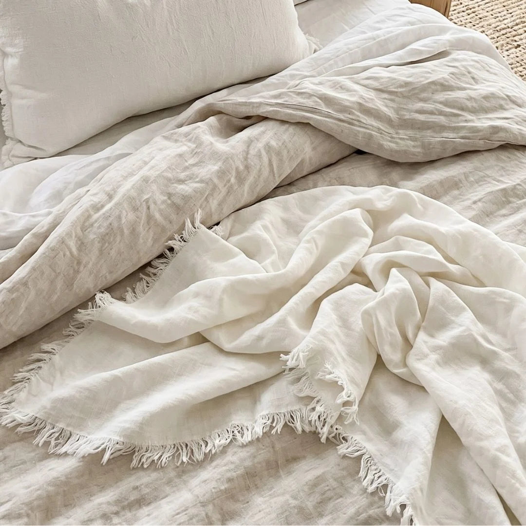 chalk white textured blanket draped over a bed with pillows
