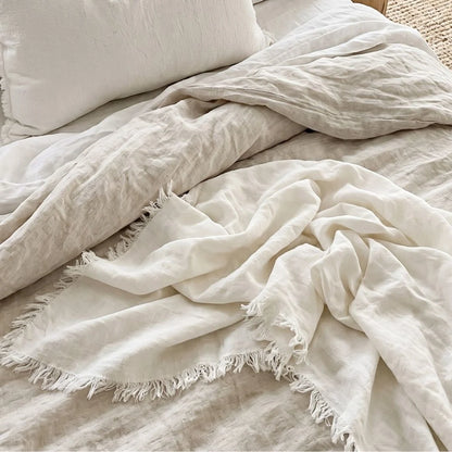 chalk white textured blanket draped over a bed with pillows