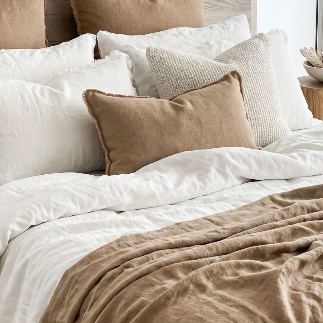 Neatly made bed with white and beige pillows and duvet