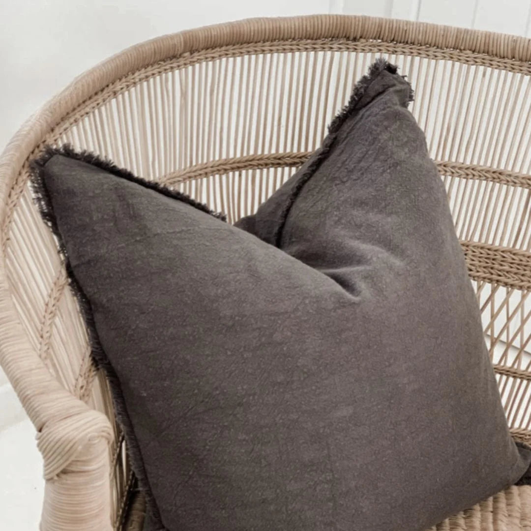 Charcoal Ramie Linen cushion on a wicker chair with a neutral background