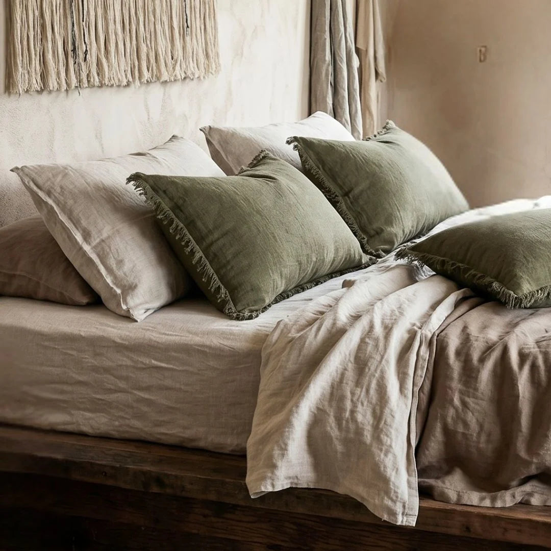 Bed with green and beige pillows and bedding in a cozy bedroom setting.
