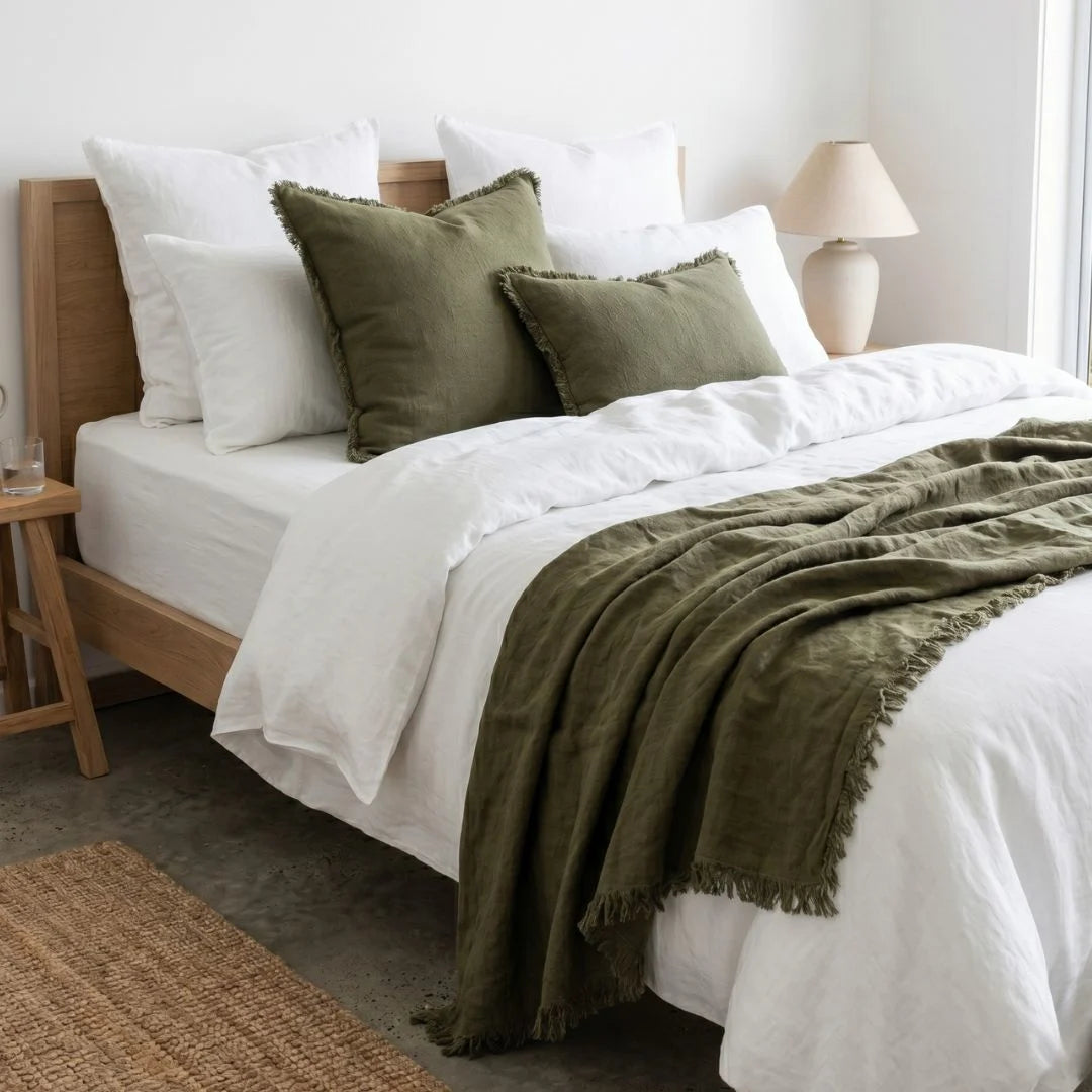Bedroom with a bed featuring white bedding and green pillows and blanket.