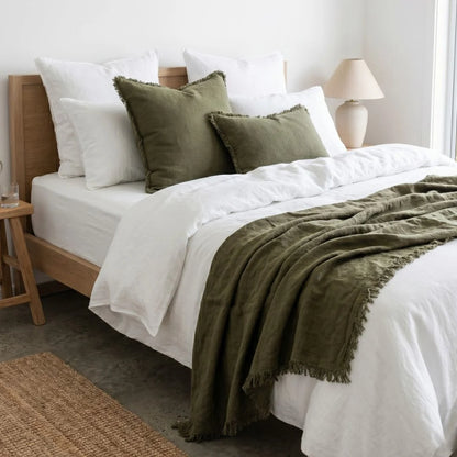 Bedroom with a bed featuring white bedding and green pillows and blanket.
