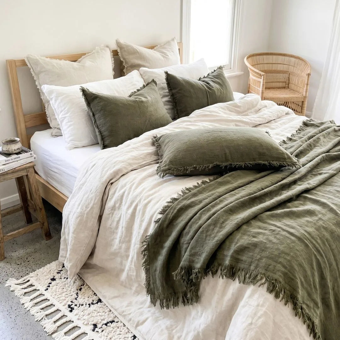 Neatly made bed with green and white bedding in a bright bedroom.