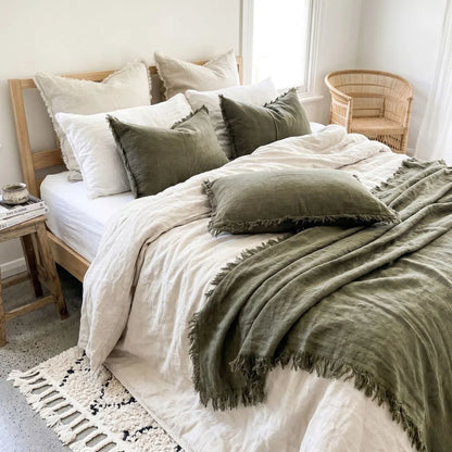 Neatly made bed with green and white bedding in a bright bedroom.