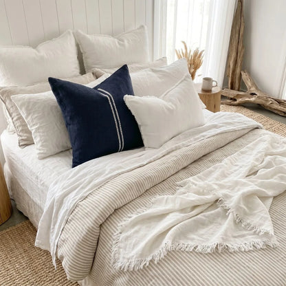 Neatly made bed with white bedding and a blue pillow in a bright bedroom.