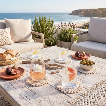 Outdoor setting with a table by the sea, featuring drinks, snacks, and decorative items.