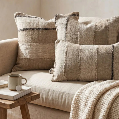 Beige sofa with textured pillows and a wooden side table featuring a mug and book.