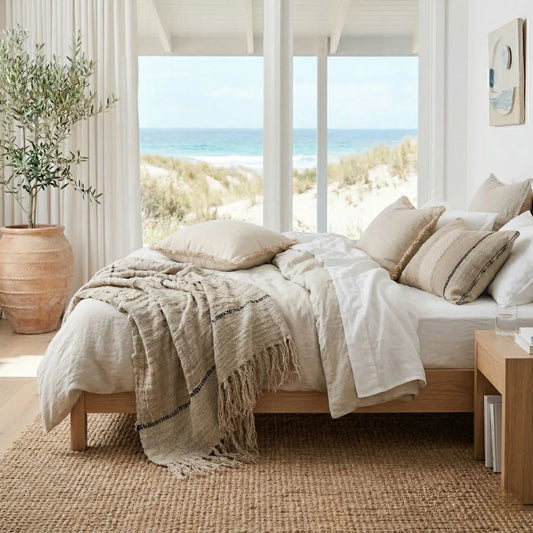 Bedroom with a view of the ocean through large windows, featuring neutral tones and natural light.