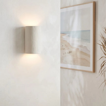 Framed beach scene art on a wall with a lamp and plant