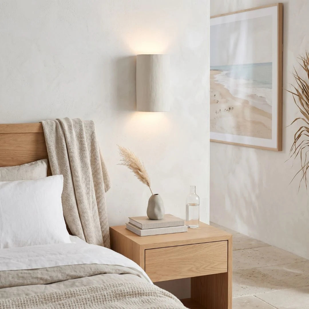 Neatly arranged bedroom with wooden bed and nightstand, featuring a lamp and decorative items.