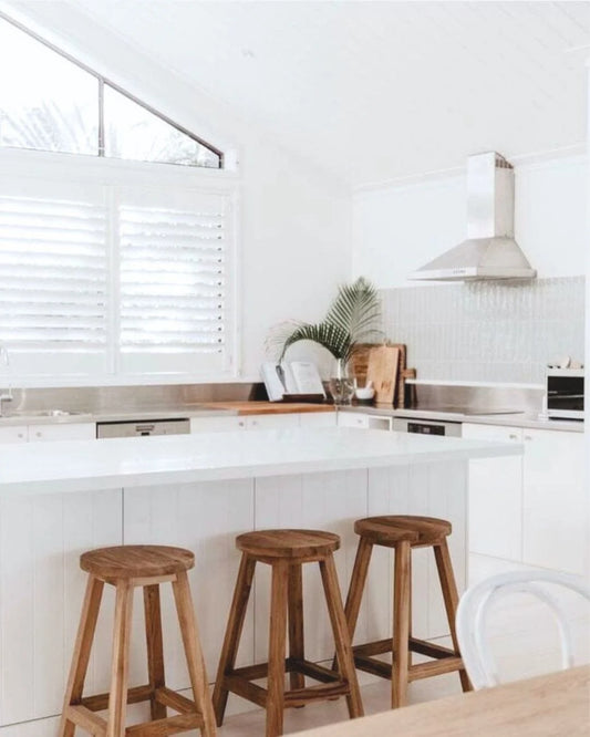 Modern kitchen with round teak counter stools and white countertops