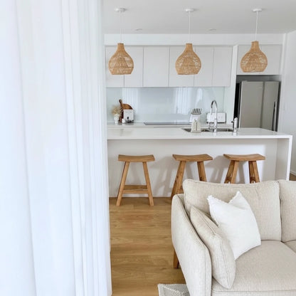 Living room with beige sofa and wooden floor, leading to a kitchen area.