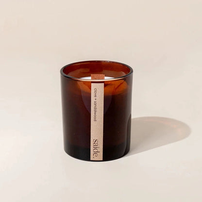 Amber glass candle with a wooden wick on a beige background