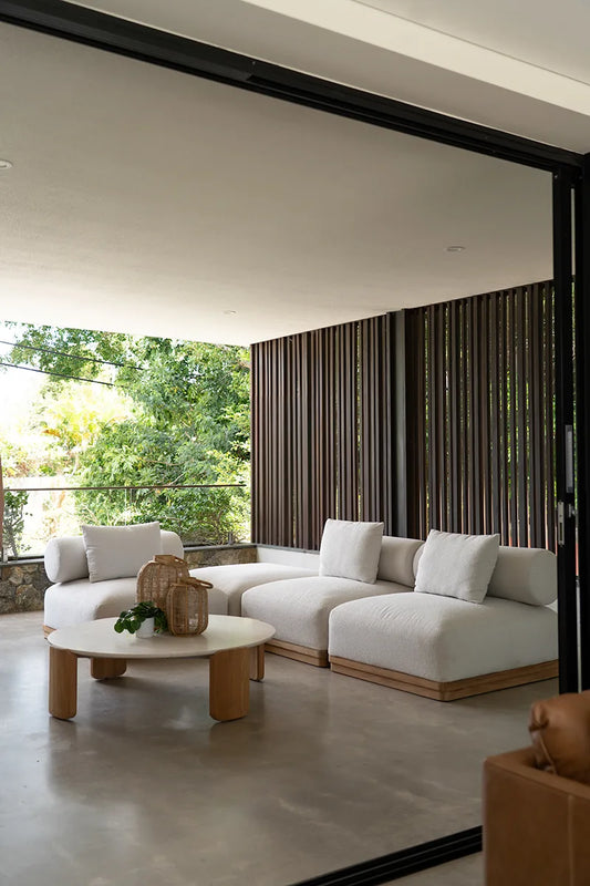 Modern living room with white sofa, wooden coffee table, and large windows.