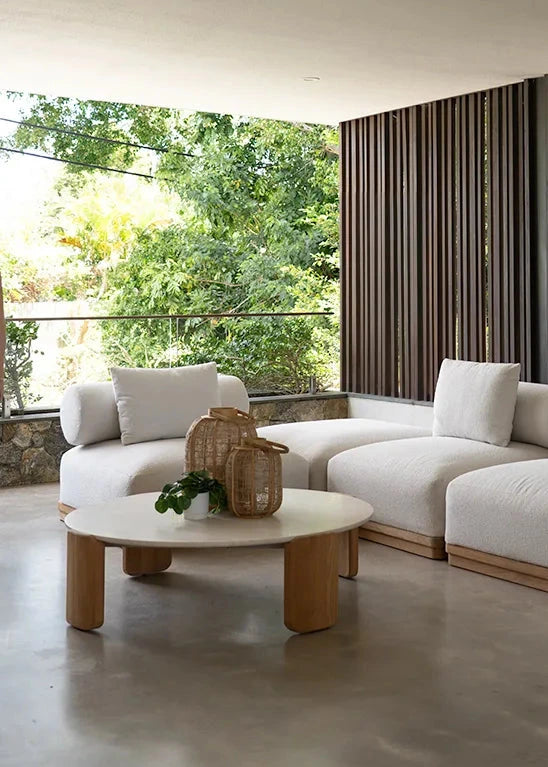 Modern living room with white sofa, wooden coffee table, and large windows.