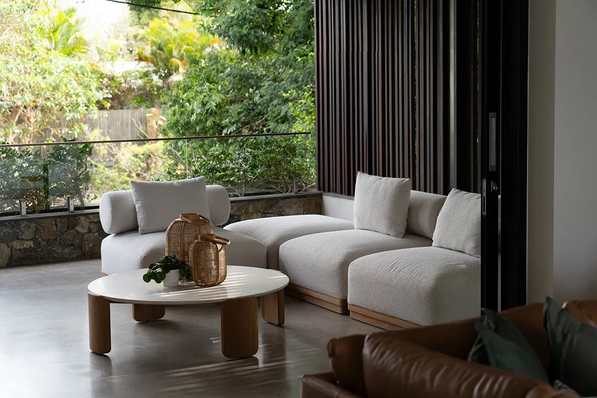 Modern outdoor patio with a white sectional sofa, wooden coffee table, and decorative items.