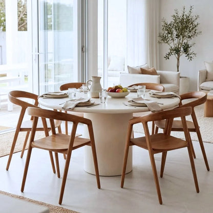 Dining area with a round table and wooden chairs in a bright room.