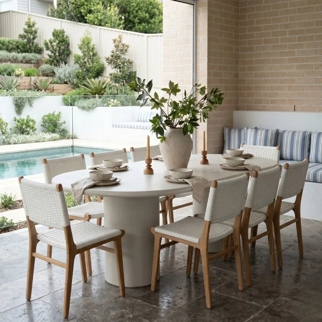 Outdoor dining area with a round table and chairs near a pool.