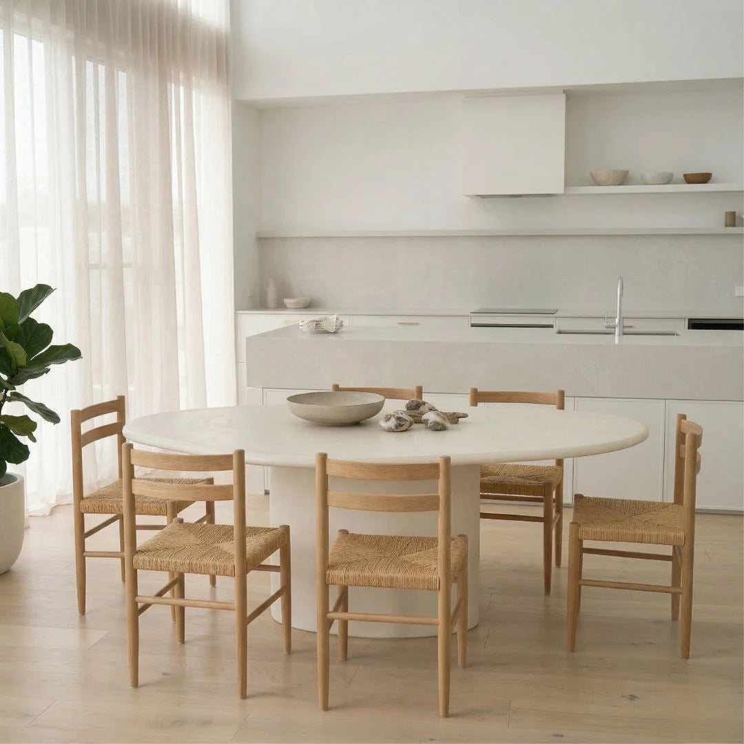 Dining area with a round white table and wooden chairs in a modern kitchen.
