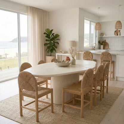 Modern dining area with a round white table and wicker chairs in a bright room.