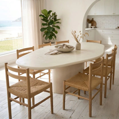 Dining area with a white table and wooden chairs in a bright room.