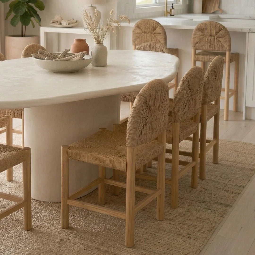Dining room with a round marble table and wicker chairs.