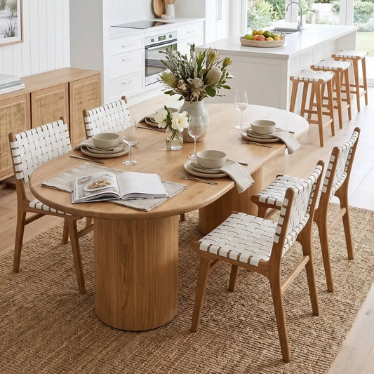 Dining room with wooden table and chairs, books, and flowers.