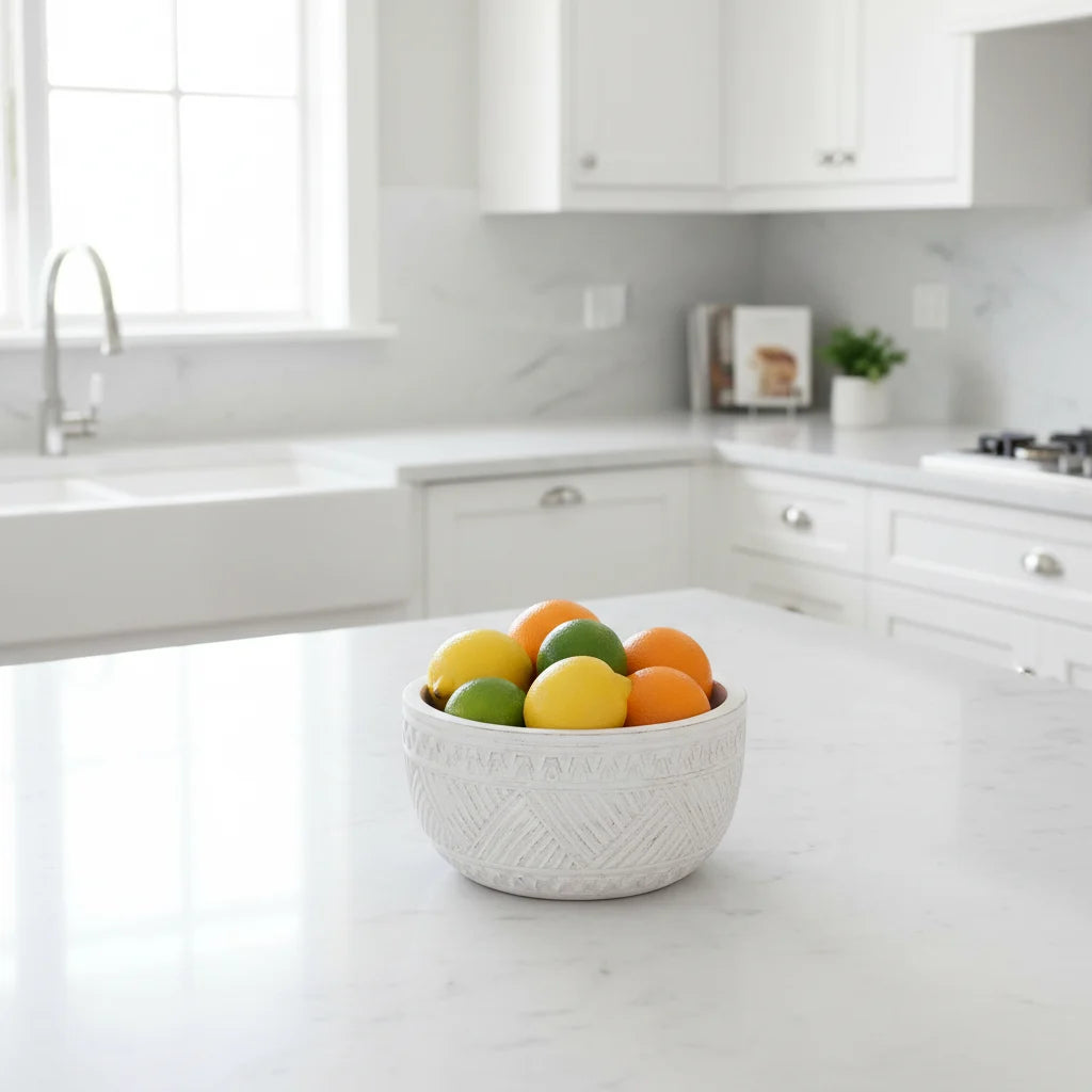 Bowl of colorful fruit on a kitchen counter with white cabinets and a window in the background
