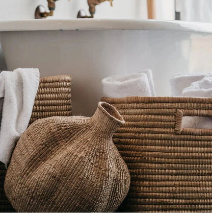 Bathroom with a freestanding bathtub, woven baskets, and brass fixtures.