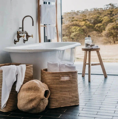 Bathroom with freestanding bathtub, wicker baskets, and a view of nature.