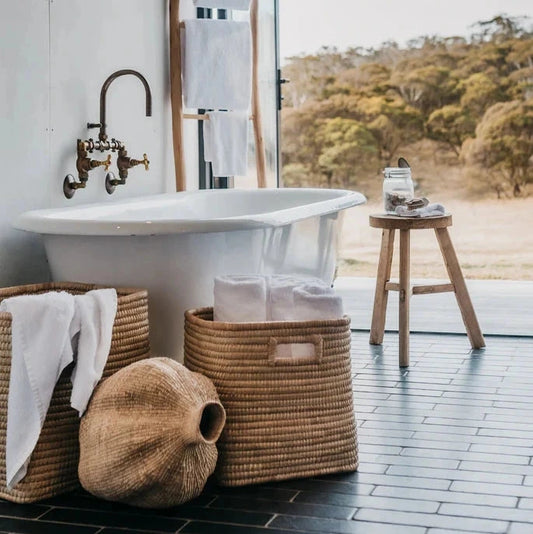 Bathroom with freestanding bathtub, wicker baskets, and a view of nature.