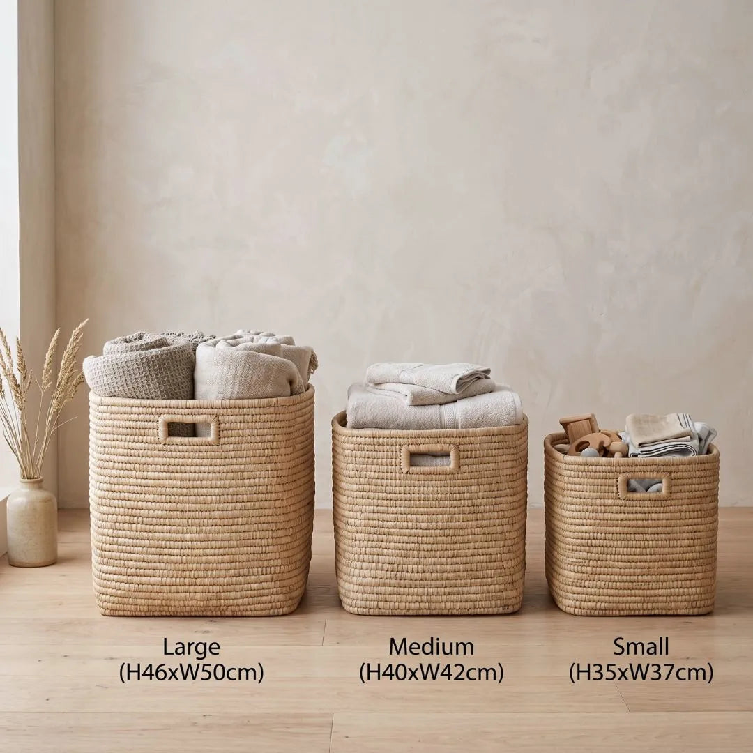 Three woven baskets of different sizes with labels on a wooden floor.