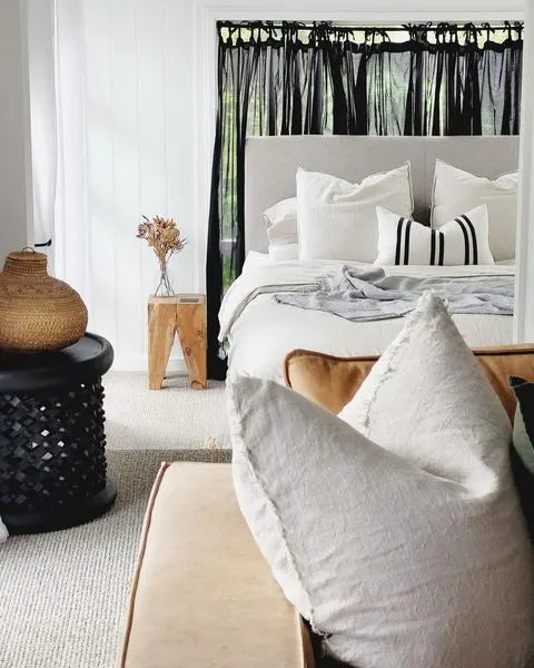 Cozy bedroom with a bed, pillows, and a square teak peg side table.