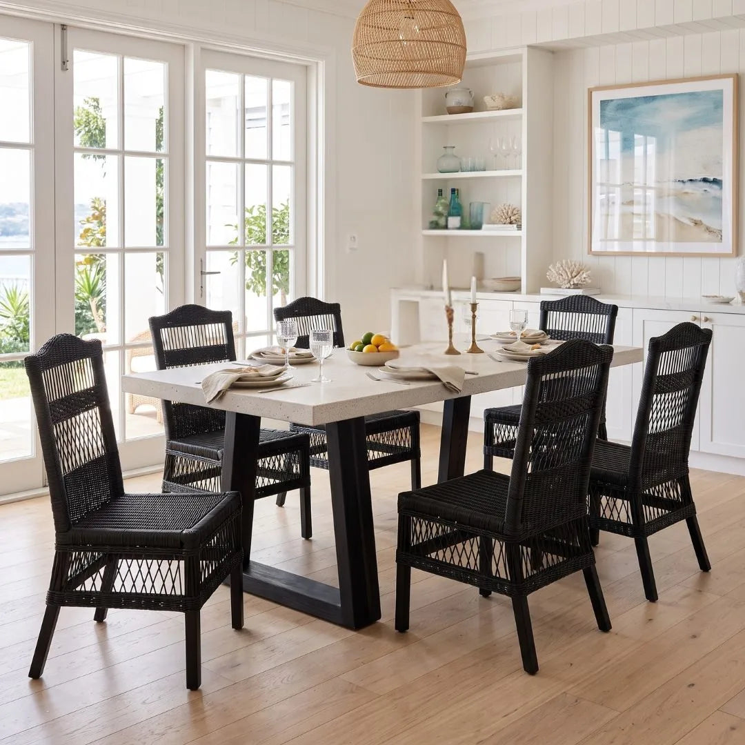 Dining room with a table and black chairs in a bright room.