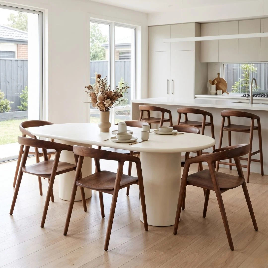Dining area with a white table and wooden chairs in a modern kitchen.