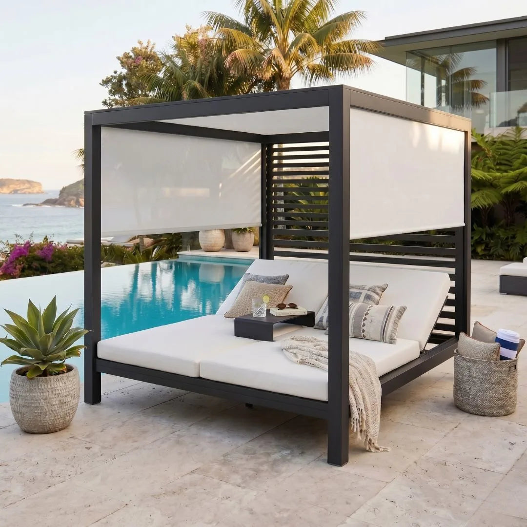 Outdoor patio cabana with white cushions by a poolside with ocean view