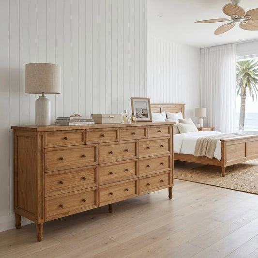 Wooden dresser in a bedroom with a bed and lamp in the background