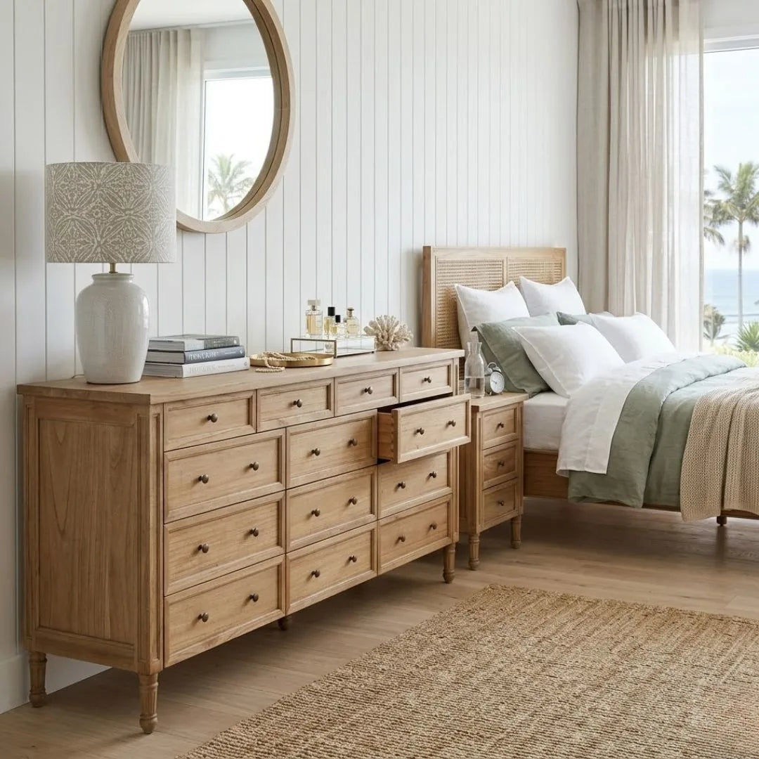 Wooden dresser in a bedroom with a bed and lamp.
