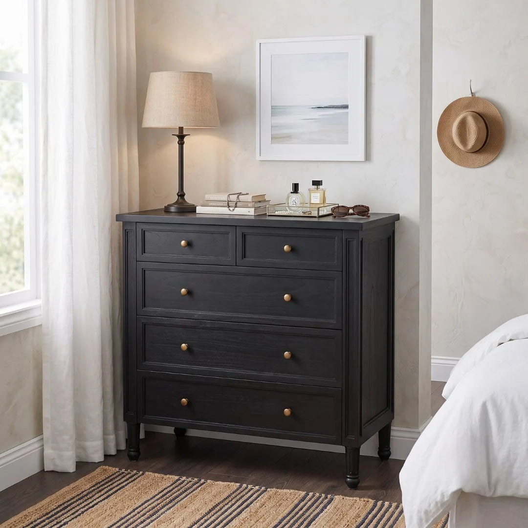 Dark wood dresser with gold knobs in a bedroom setting.