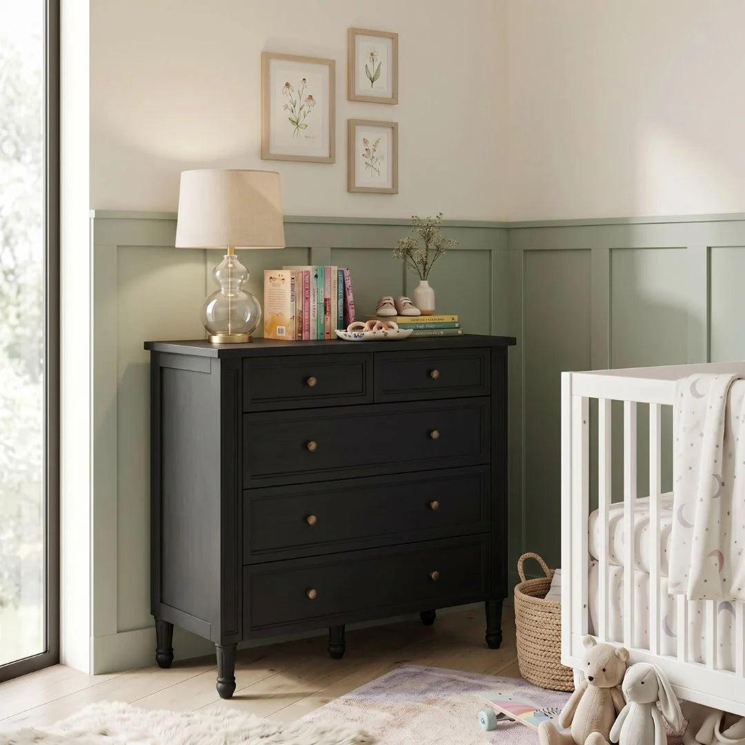 Nursery room with a black dresser, white crib, and decorative elements.