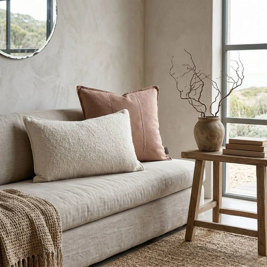 Cozy living room with a beige sofa, pink pillows, and a wooden side table with decor items.
